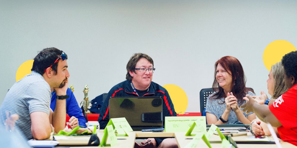 Group of people in an office table talking and smiling
